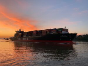 red cargo ship on sea during sunset